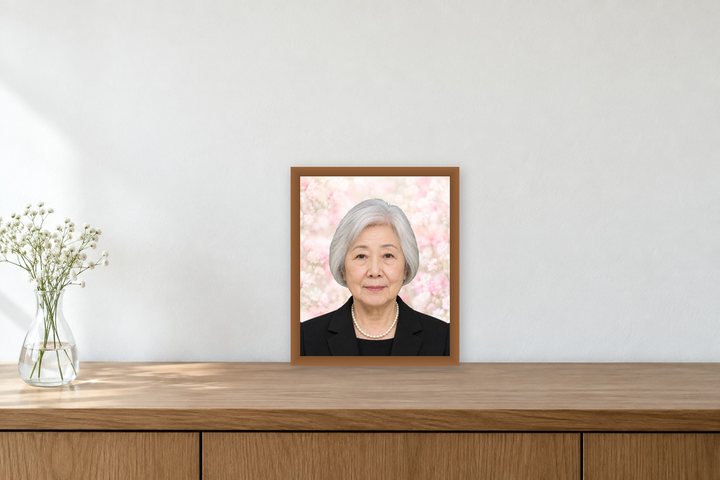 木の棚の上に、花を挿した花瓶と一緒に置いた、銀髪の女性の小さい遺影の見本（架空の人物）